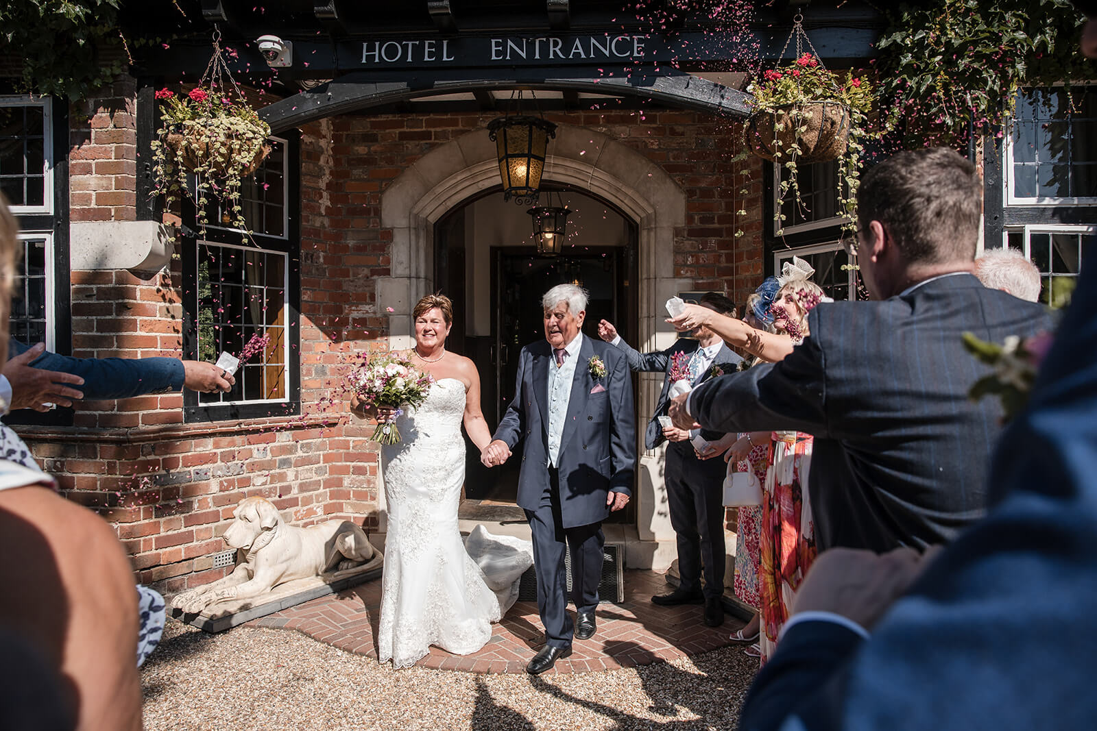 Brenda and David walking through confetti outside The Montagu Arms Hotel in Beaulieu