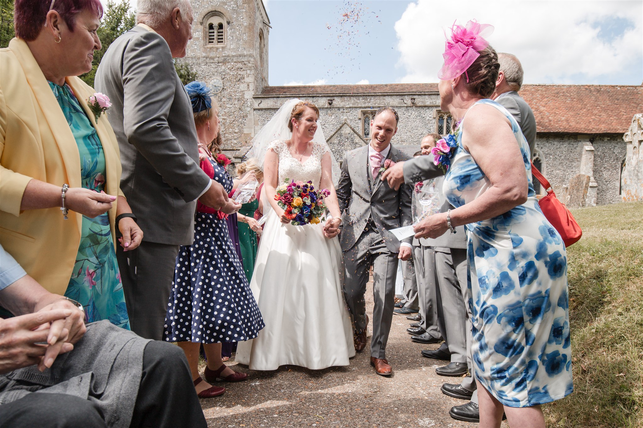 Abby and Matt walking through confetti outside St Michael & All Angels Church in Figheldean, Salisbury.
