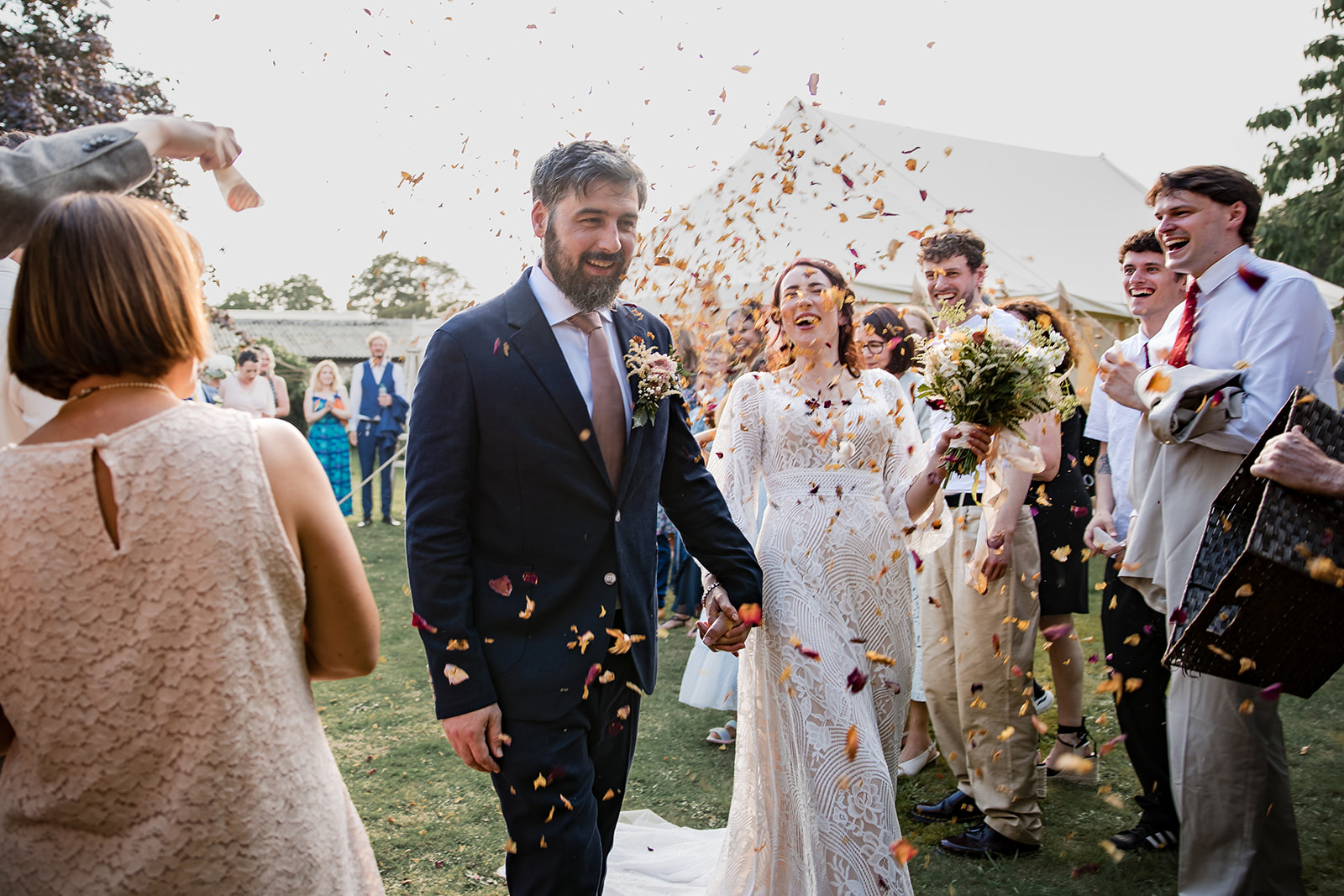 Anna and Alex walking through confetti during their bohemian wedding near Winchester.