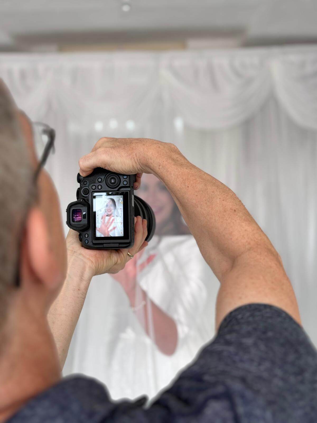 Photographer capturing a bride through a veil during wedding preparations.