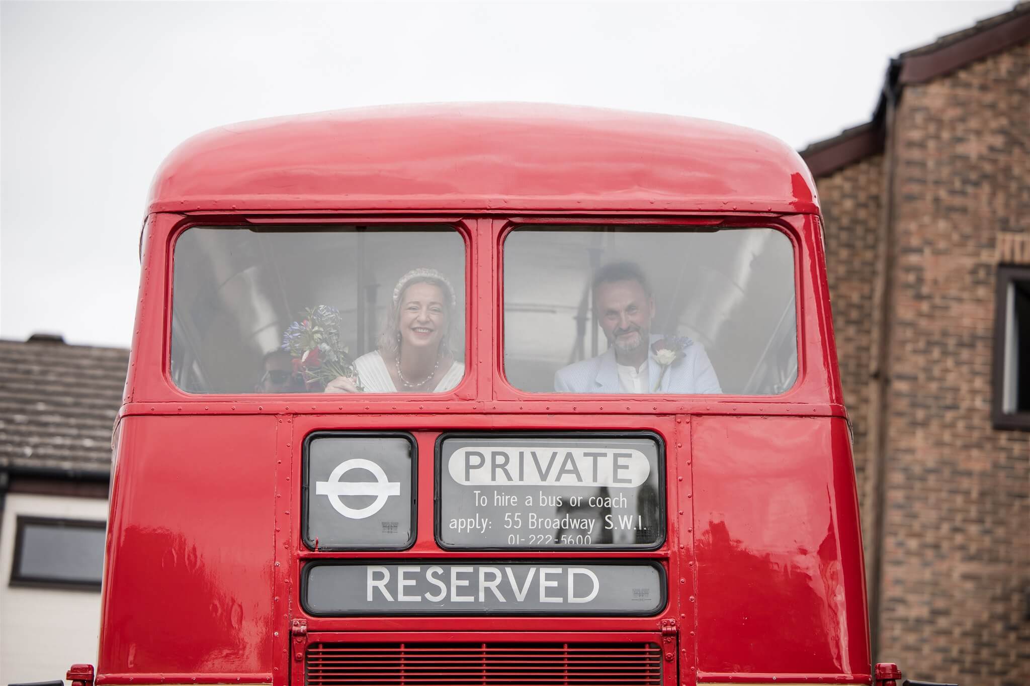 Adrienne and Bob arriving at Westgate Hall for their wedding in Southampton on a red double-decker bus.