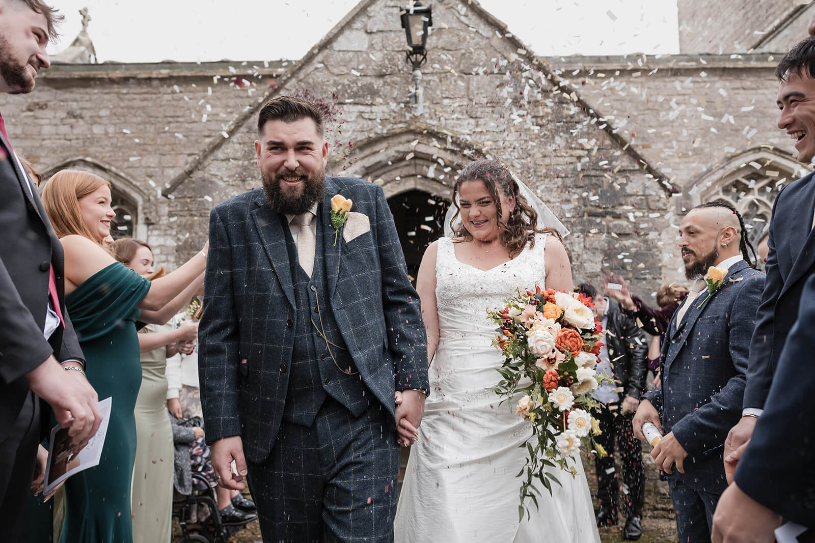 Connie and Sam walking through confetti outside St Andrew’s Church during their Weymouth wedding.